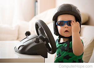Child wearing a racing helmet and sunglasses, sitting in front of a video game racing wheel.